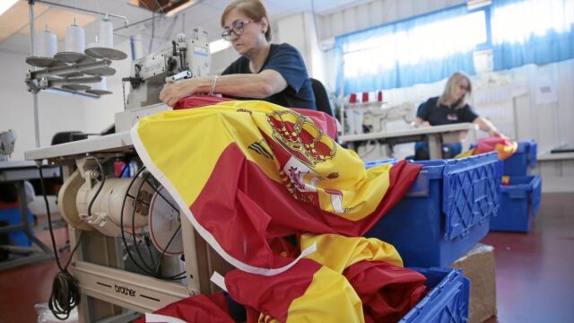 Una trabajadora de la empresa Sosa-Dias remata una de las banderas de España que fabrican
