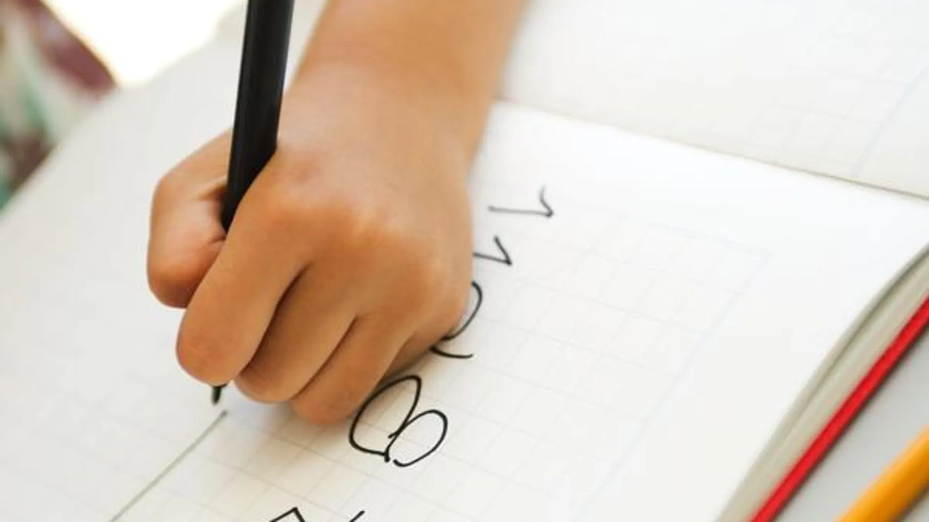 Un niño zurdo escribe en un cuaderno