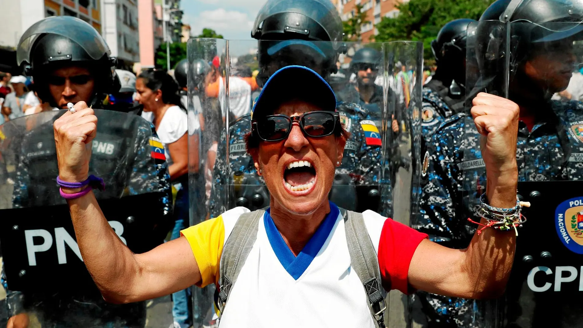 Un miembro de la oposición celebra el éxito de la protesta de ayer entre varios policías / Reuters