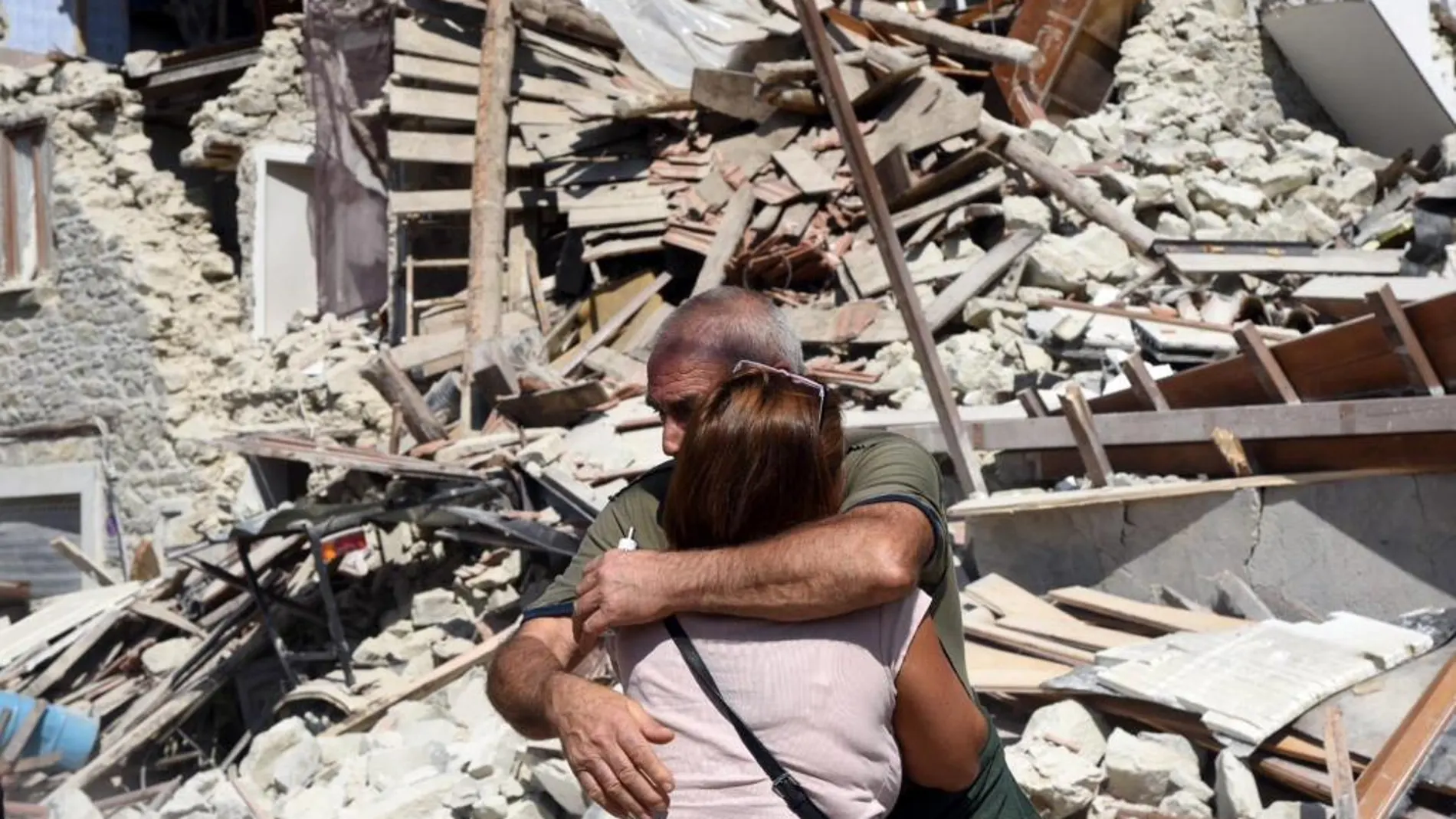 Dos lugareños se abrazan ante varias casas derrumbadas en Pescara del Tronto, cerca de la localidad de Arquata del Tronto.