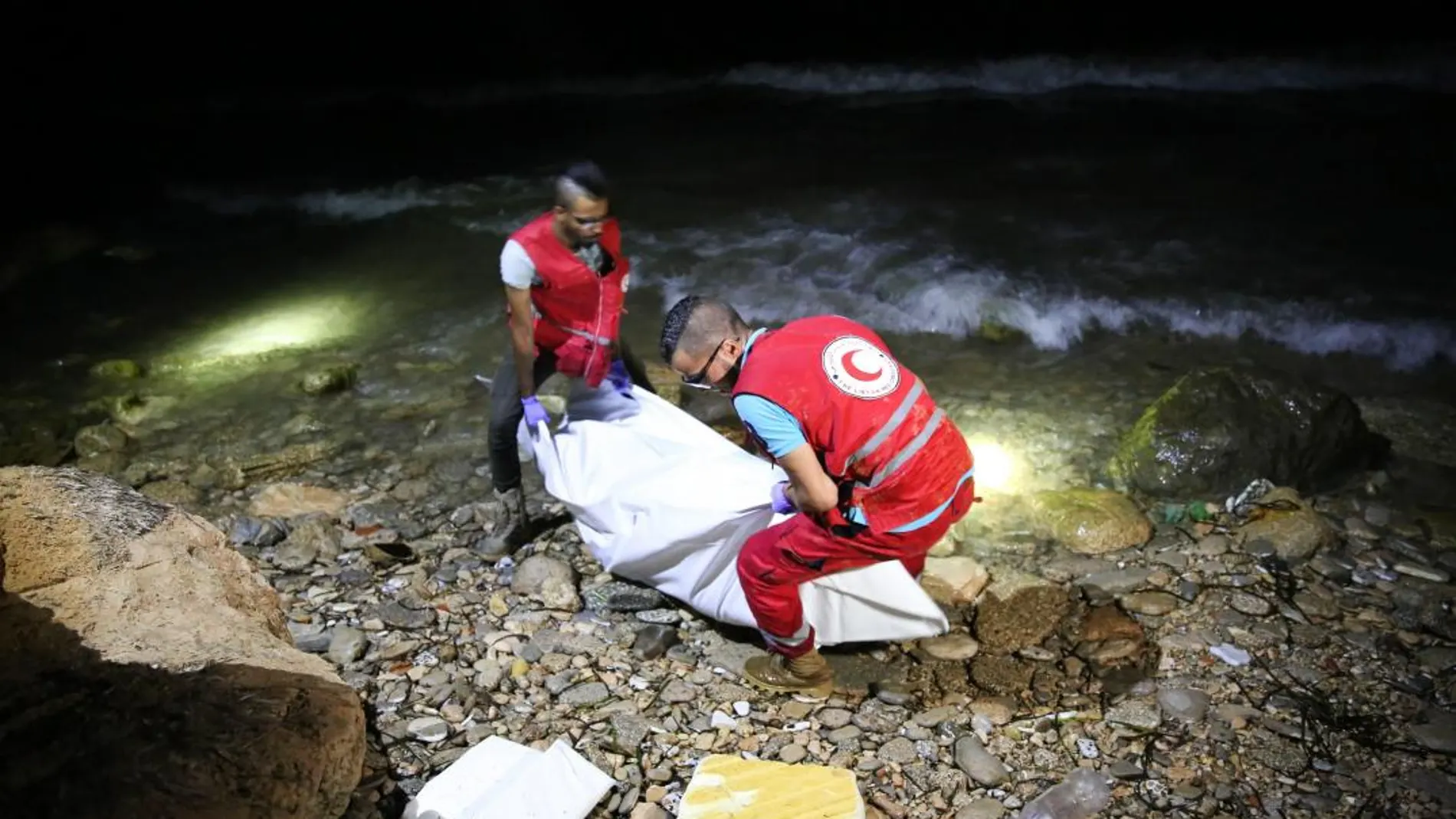 Personal de rescate de la Media Luna Roja Libia (LRC según sus siglas en inglés) transportan el cuerpo de un inmigrante fallecido ahogado en la playa de Tajura, a 14km de Tripli, Libia, el 2 de julio de 2018