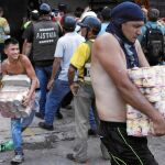 Varios venezolanos cargan con productos de primera necesidad tras el asalto a un supermercado de Táchira