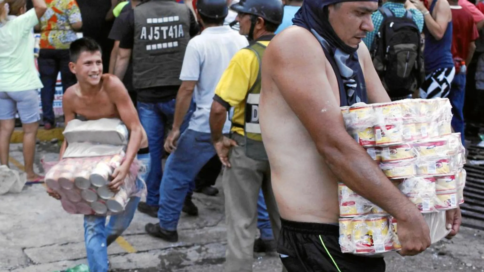 Varios venezolanos cargan con productos de primera necesidad tras el asalto a un supermercado de Táchira