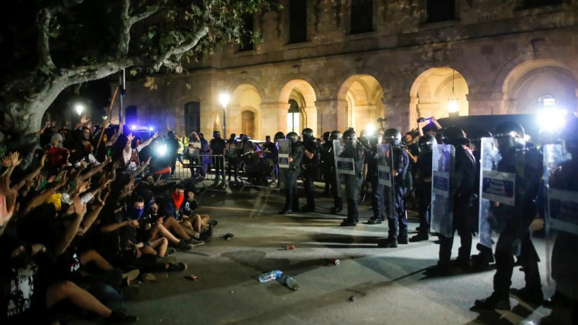 Manifestantes ante los Mossos en el Parlament de Cataluña.