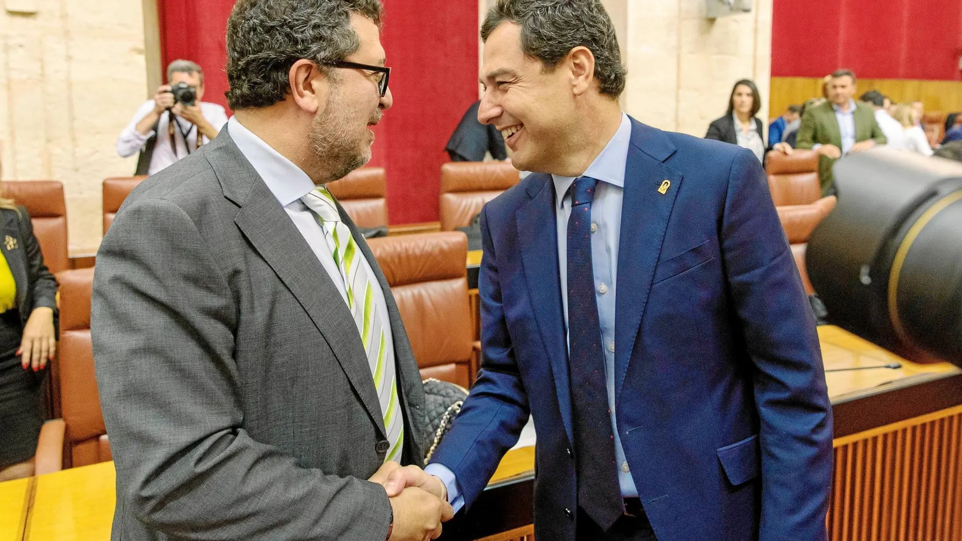 El presidente andaluz, Juanma Moreno (dcha.), saluda ayer antes del Pleno parlamentario al portavoz de Vox Francisco Serrano (dcha.) / Efe