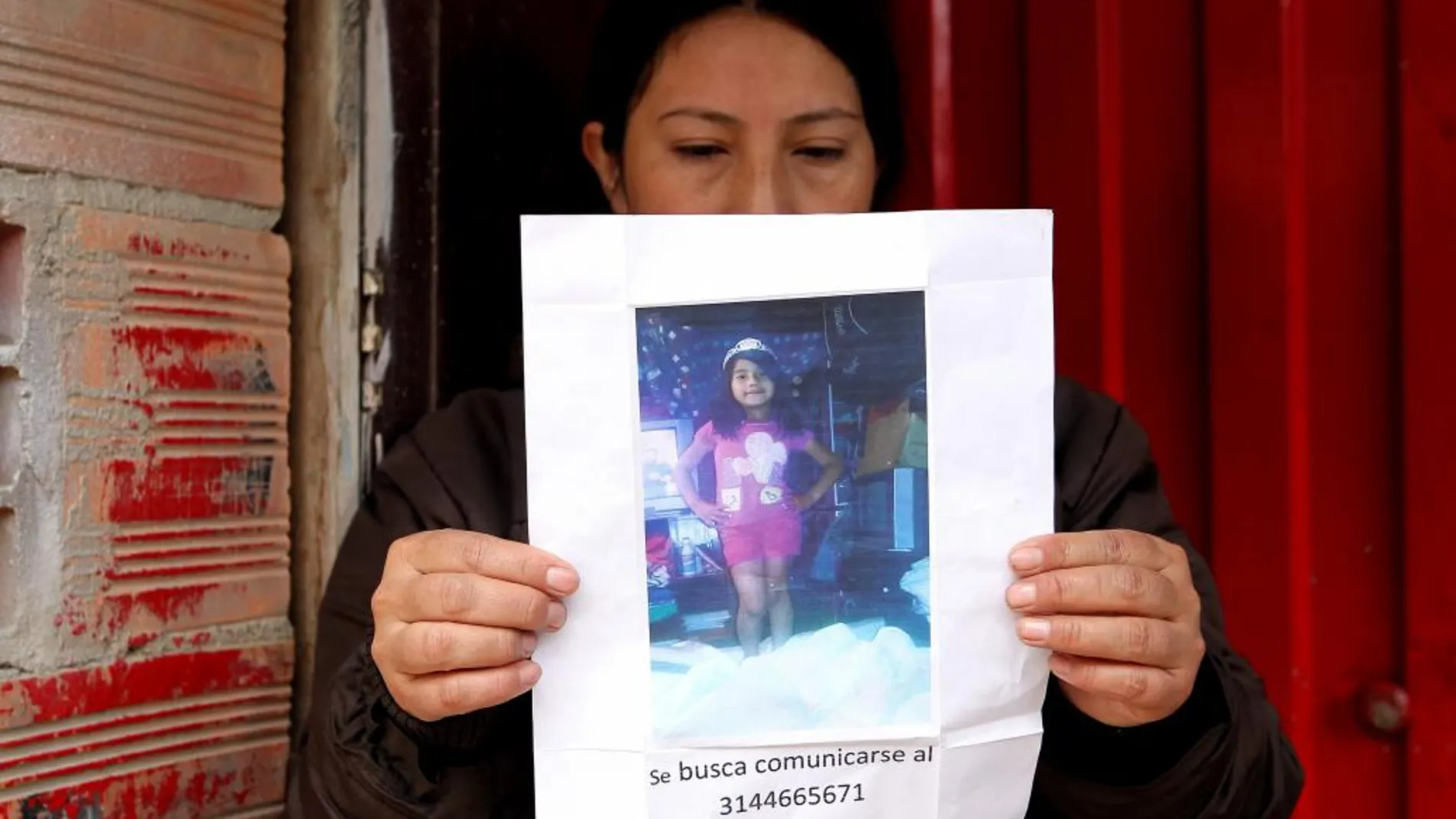 Una mujer sostiene un papel con la fotografía de la niña Yuliana Andrea Samboni Muñoz hoy, martes 5 de diciembre de 2016, en Bogotá (Colombia).