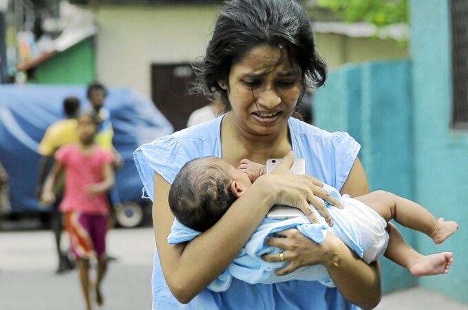 Una mujer corre con su bebé tras la explosión ayer de un vehículo aparcado en una calle de Colombo, la capital de Sri Lanka / Ap