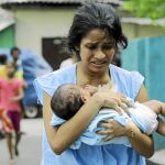 Una mujer corre con su bebé tras la explosión ayer de un vehículo aparcado en una calle de Colombo, la capital de Sri Lanka / Ap