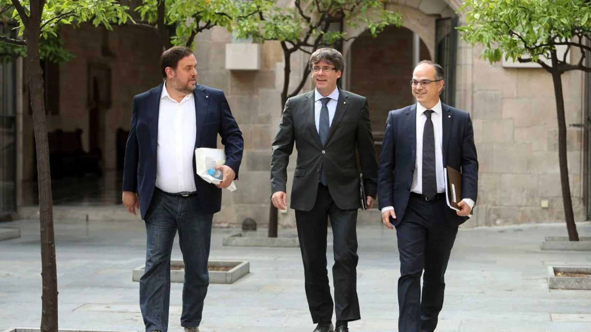 El presidente de la Generalitat, Carles Puigdemont (d), el vicepresidente del Govern y conseller de Economía, Oriol Junqueras (i) y el conseller de la presidencia Jordi Turull
