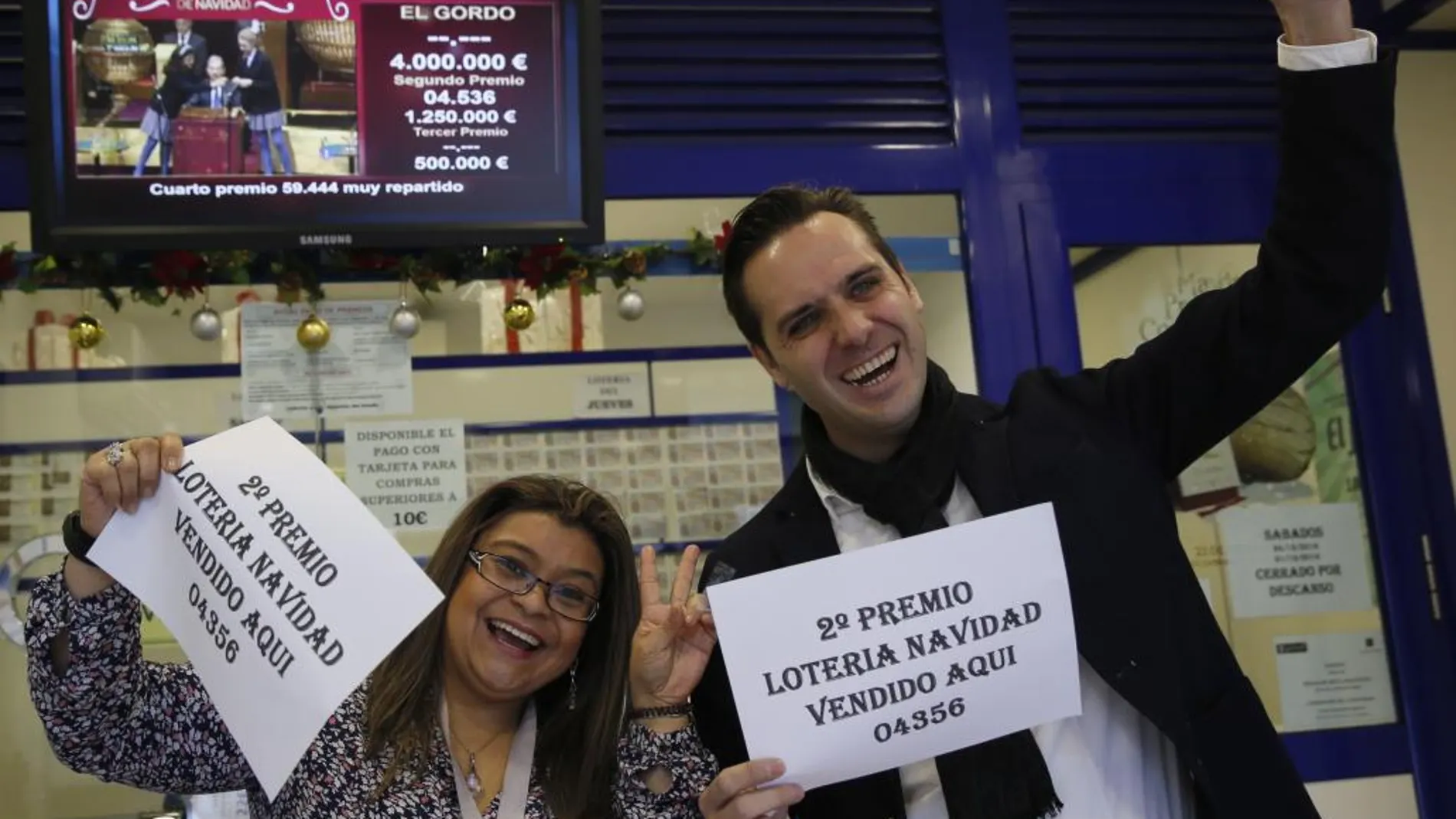 Marcos Delgado, dueño de la administración de lotería ubicada en la calle Condesa de Venadito en Madrid, acompañado de la vendedora Jenyffer Hoyos celebran su segundo premio