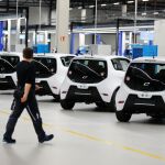 Un empleado de e.GO Mobile AG, junto a varios de los modelos eléctricos producidos por esta firma