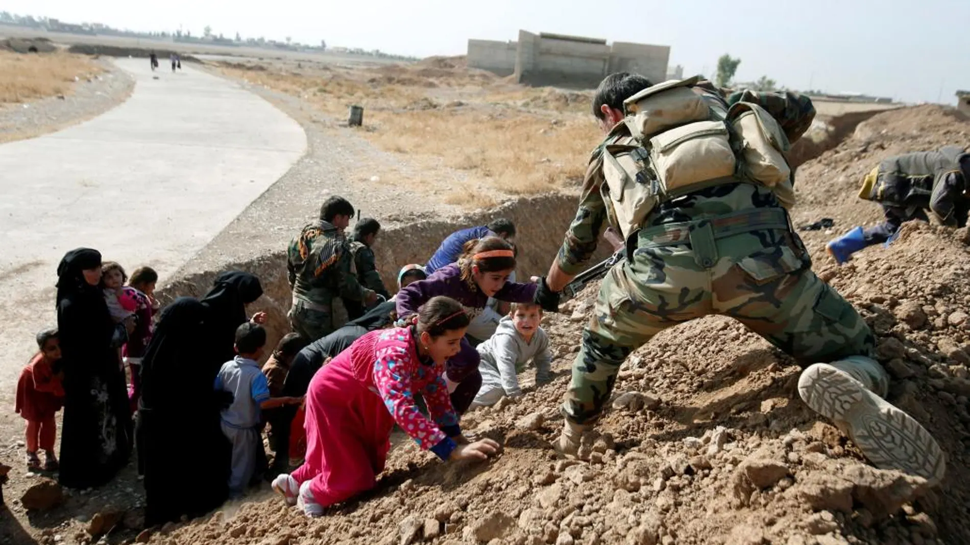 Un soldado ayuda a mujeres y niños que huyen del Estado Islámico .