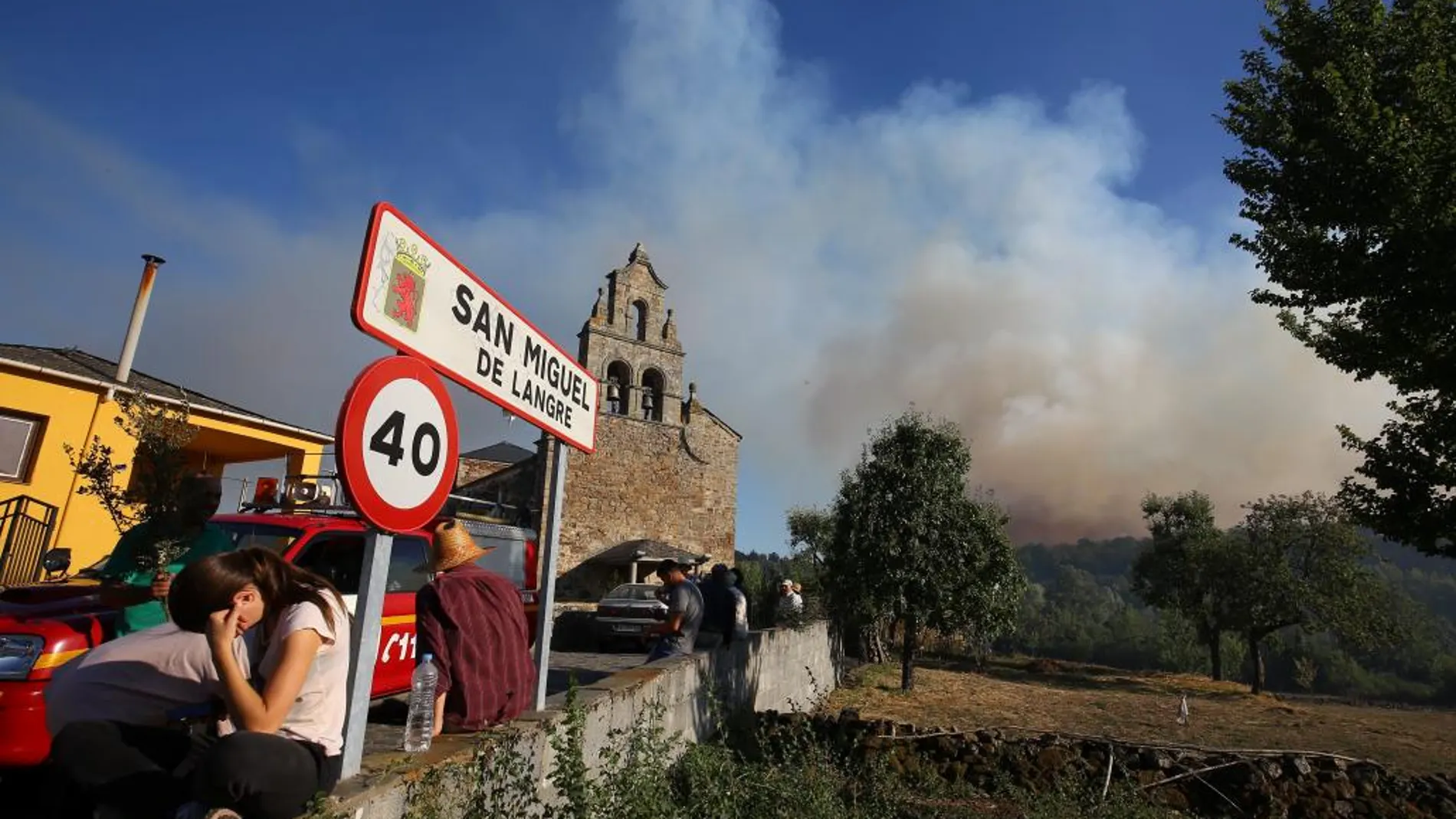 Vecinos de San Miguel de Langre observan el denso humo y las llamas acercándose sus casas