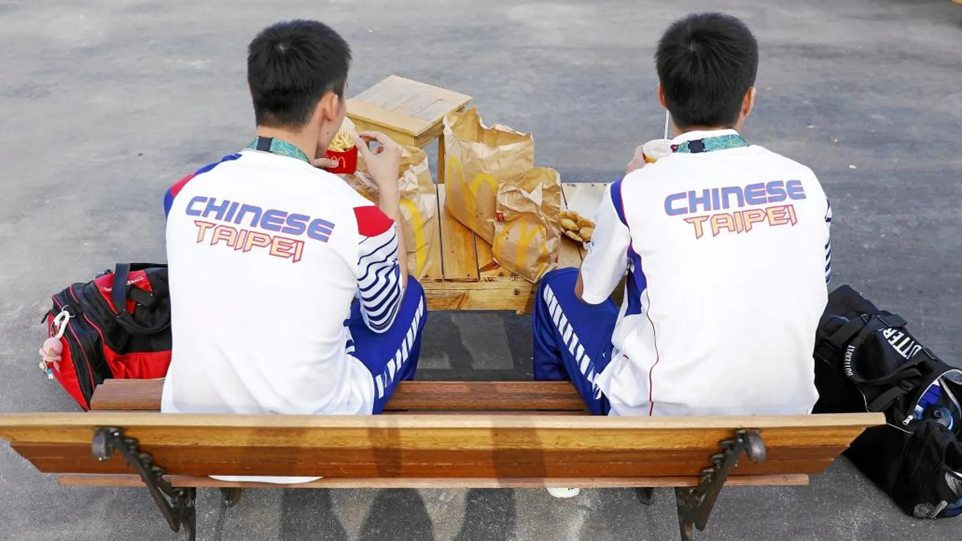 Dos atletas chinos comiendo hamburguesas en la Villa Olímpica
