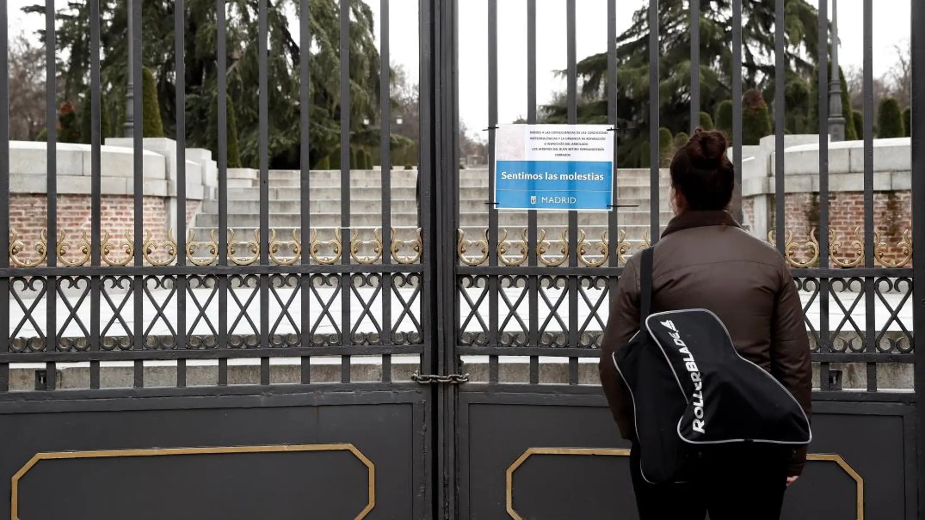 Una mujer observa un cartel alusivo al cierre del parque del Retiro de Madrid el día de la muerte de Darío