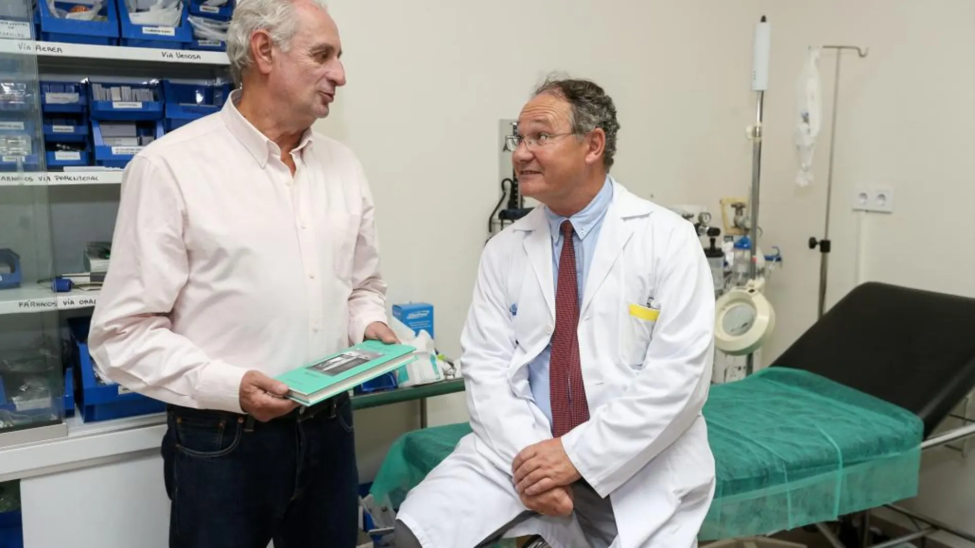 El doctor Antonio Otero conversa, en un centro hospitalario, con el editor Julio Martínez, que tiene el libro en la mano