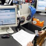 Farmacéutica comprueba la receta electrónica de un cliente en una oficina de farmacia de León