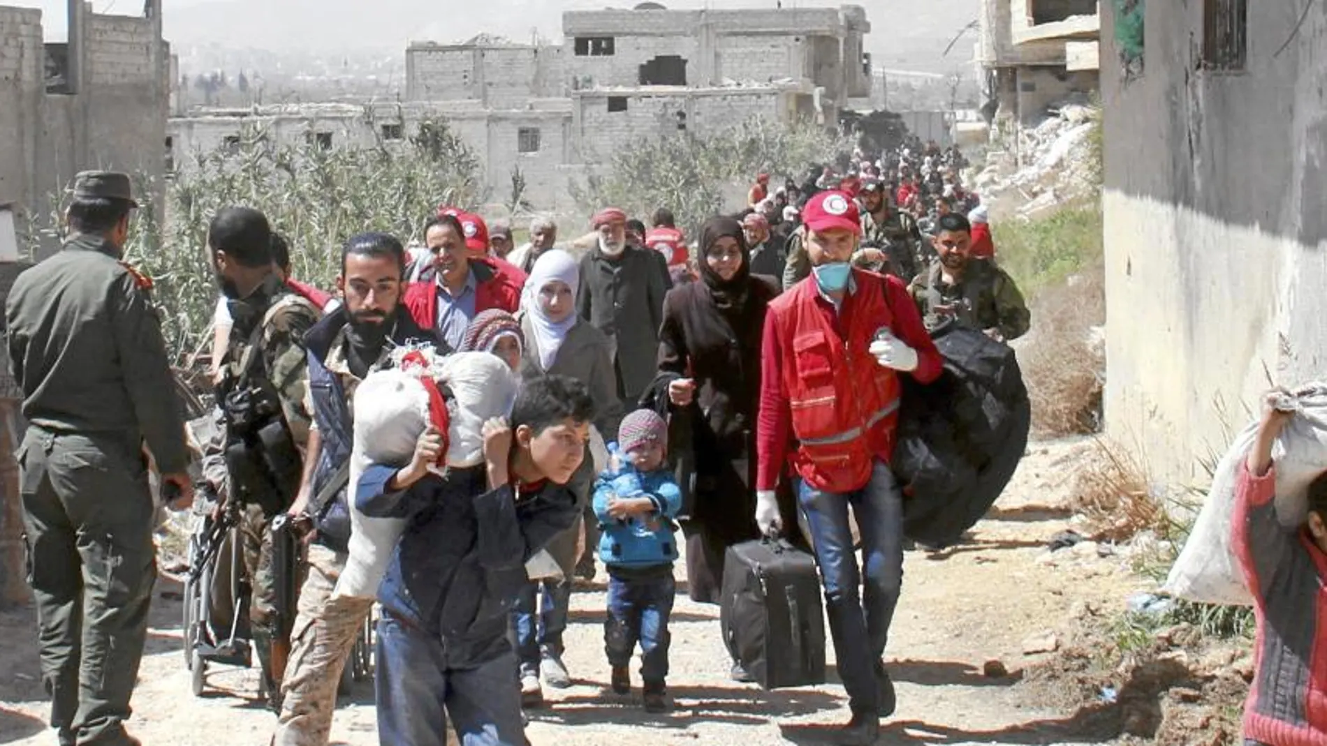 Civiles sirios cargan con sus pertenencias antes de ser evacuados ayer de la provincia de Guta Oriental con destino a Idlib