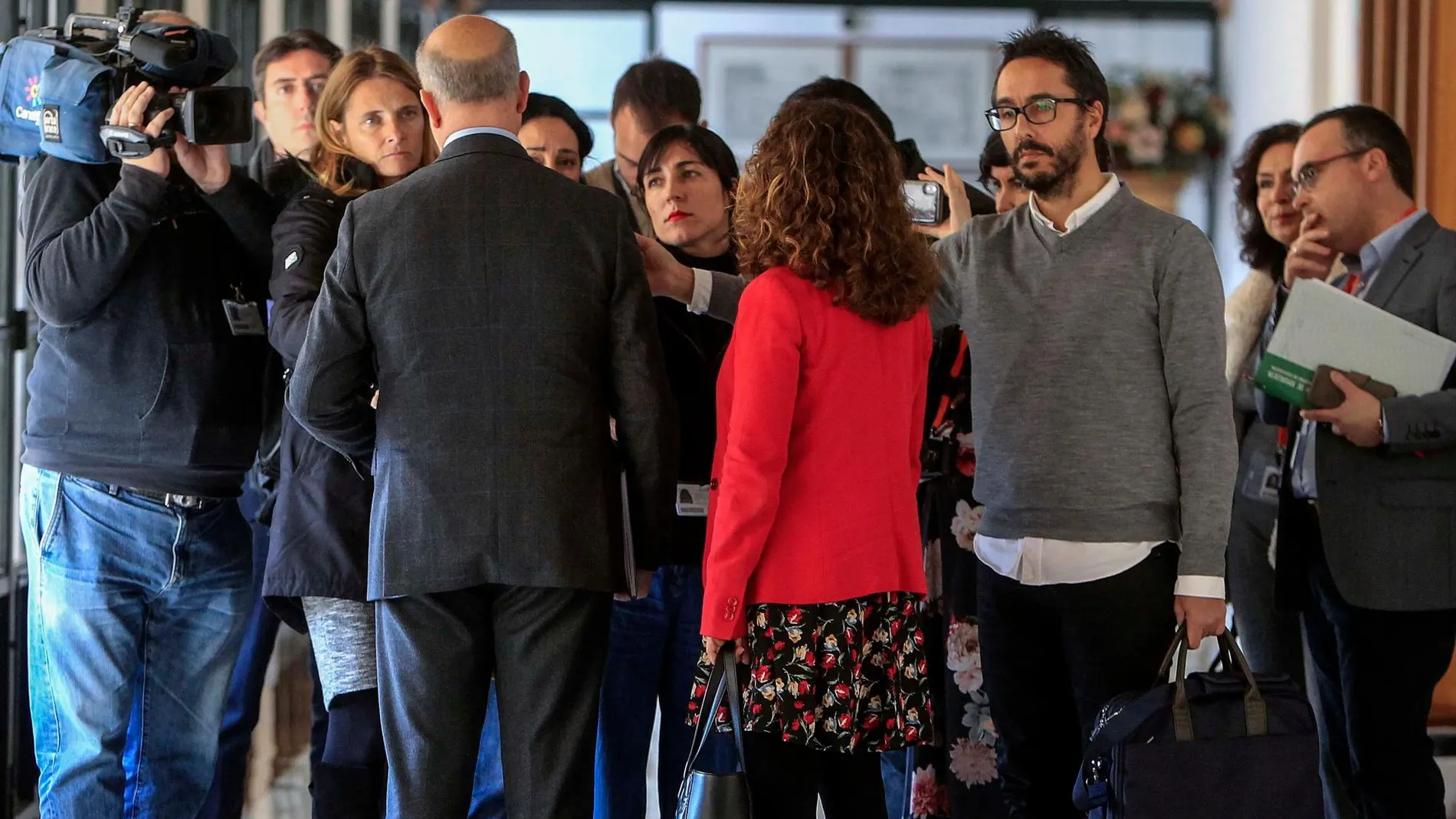 El consejero de Educación, de espaldas, atiende a la prensa en los pasillos del Parlamento / Foto: Manuel Olmedo