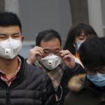 Varios peatones con mascarillas en Pekín para protegerse de la contaminación / Reuters