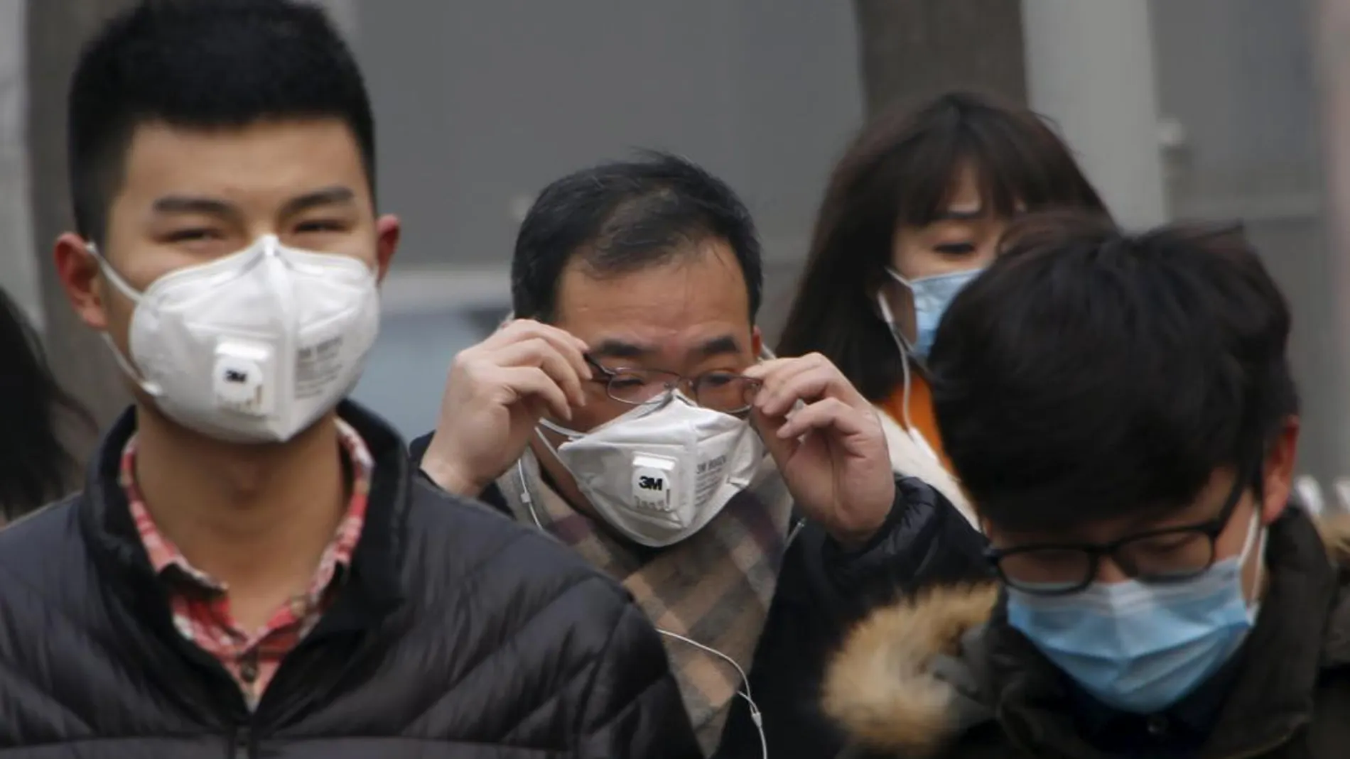Varios peatones con mascarillas en Pekín para protegerse de la contaminación / Reuters