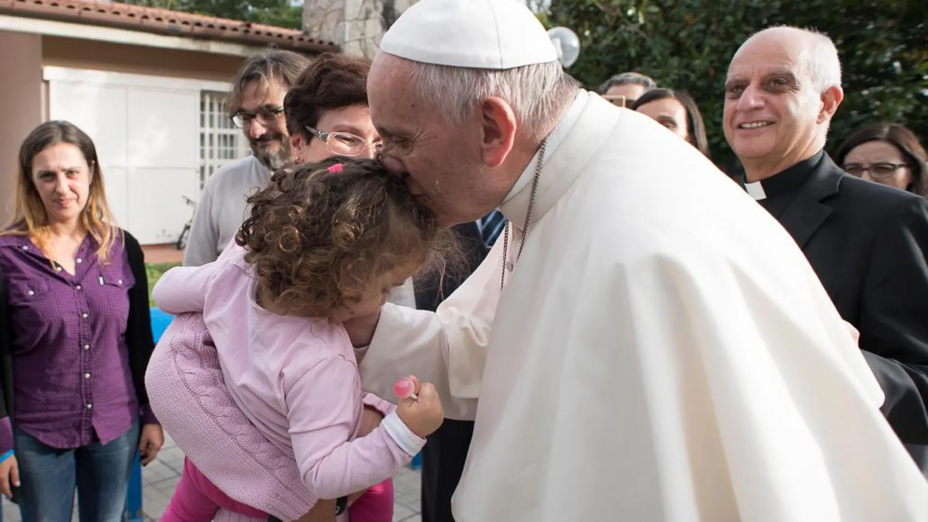 El Papa besa a un niña del centro de acogida que visitó