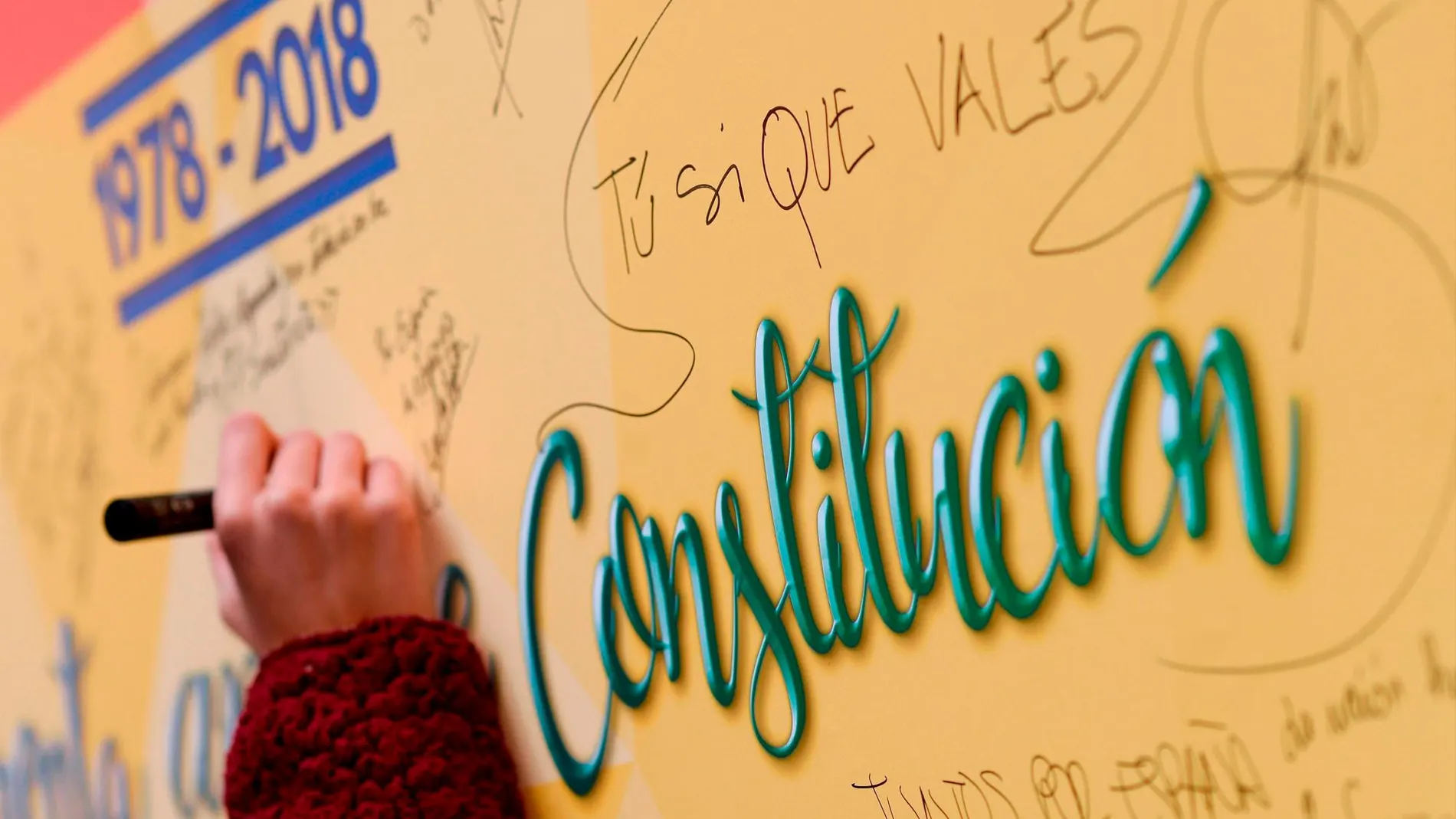 Una persona escribe su pensamiento en un muro durante el acto a favor de la Constitución en Valladolid