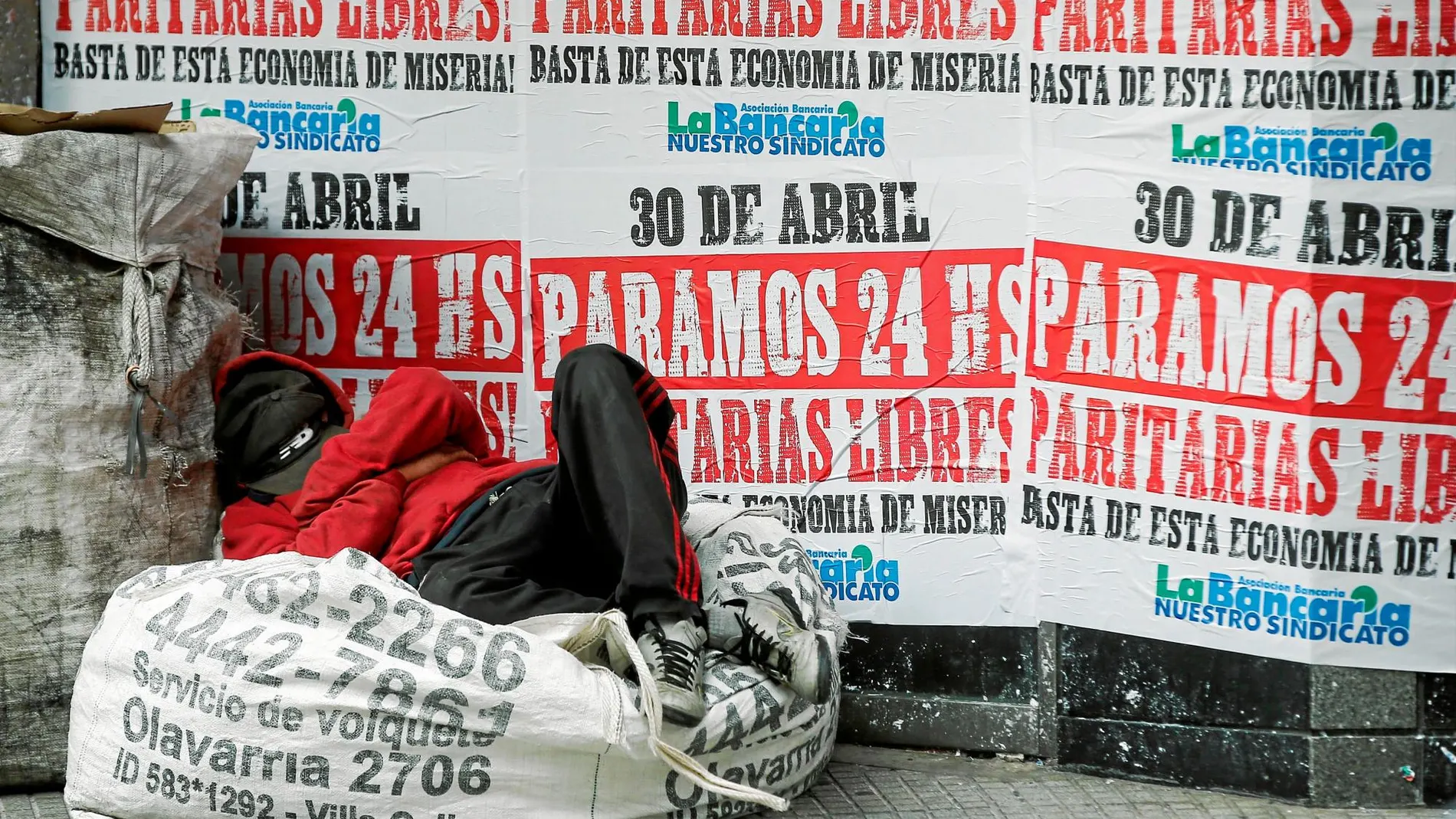 Un «sin techo» duerme en Buenos Aires junto a un local de cambio cubierto con carteles de una huelga general para mañana / Reuters