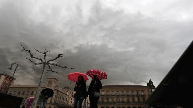 Dos personas se protegen del agua con un paraguas esta mañana en al Plaza del Castillo de Pamplona