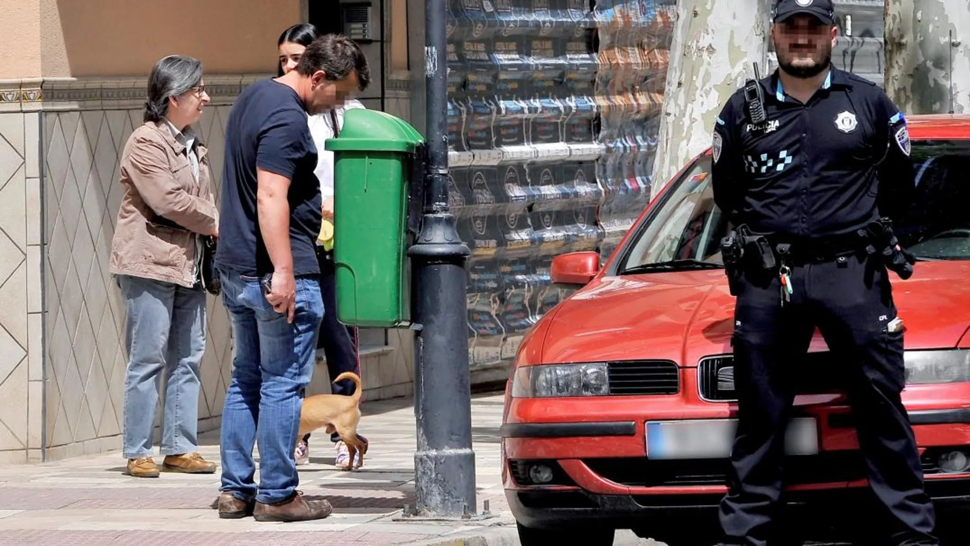 Un policía de paisano busca el arma homicida dentro de una papelera en las inmediaciones de la casa / Foto: Efe