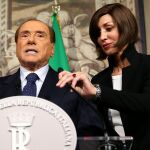 La senadora de Forza Italia, Anna Maria Bernini, coloca el micrófono de Silvio Berlusconi antes de la rueda de prensa, hoy en Roma