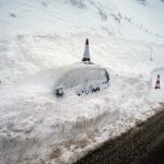 Un vehículo permanecen cubierto de nieve, en el pueblo de Pajares (N-630)