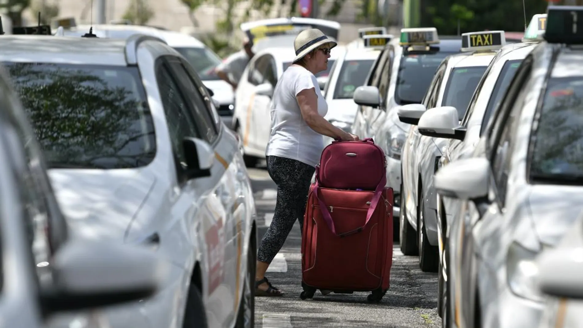 Una viajera pasa entre los taxis aparcados / Efe