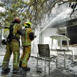 Dos bomberos tratan de sofocar las llamas en una vivienda de Marxuquera, en Gandía