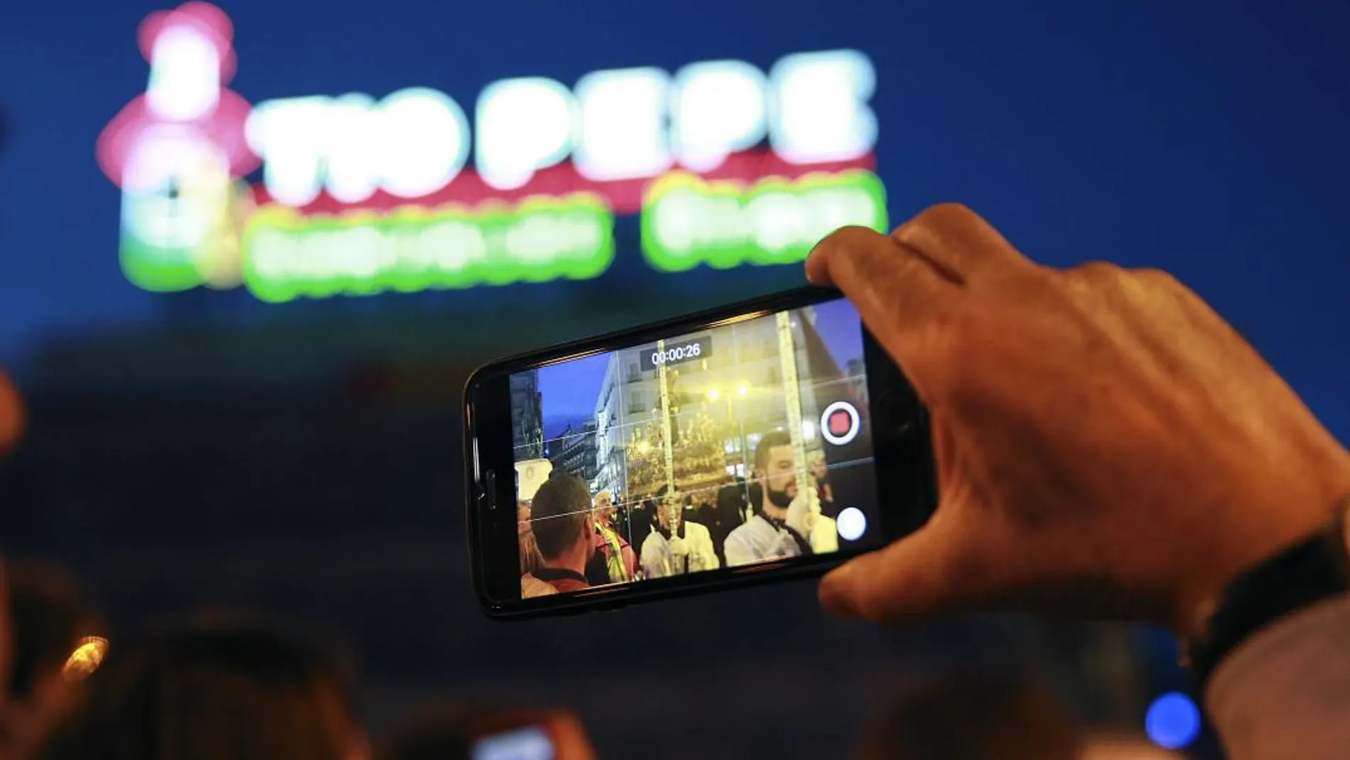 Un usuario utiliza si móvil para grabar en una procesión en Madrid