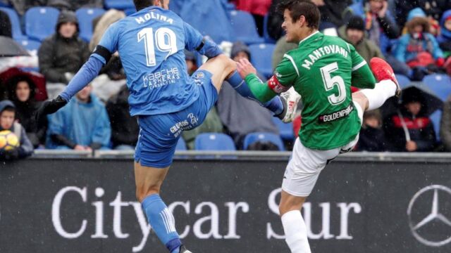El delantero del Getafe, Jorge Molina (i), y el defensa argentino del Leganés, Martín Mantovani (d), saltan por un balón.