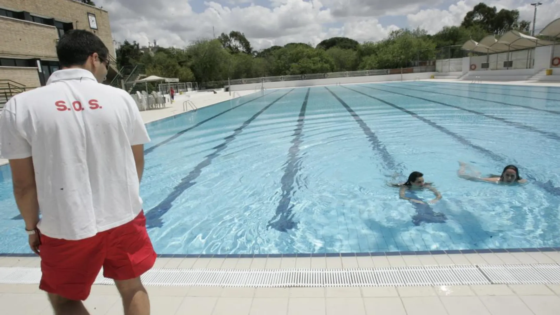 Un socorrista mira con atención a dos bañistas en una piscina