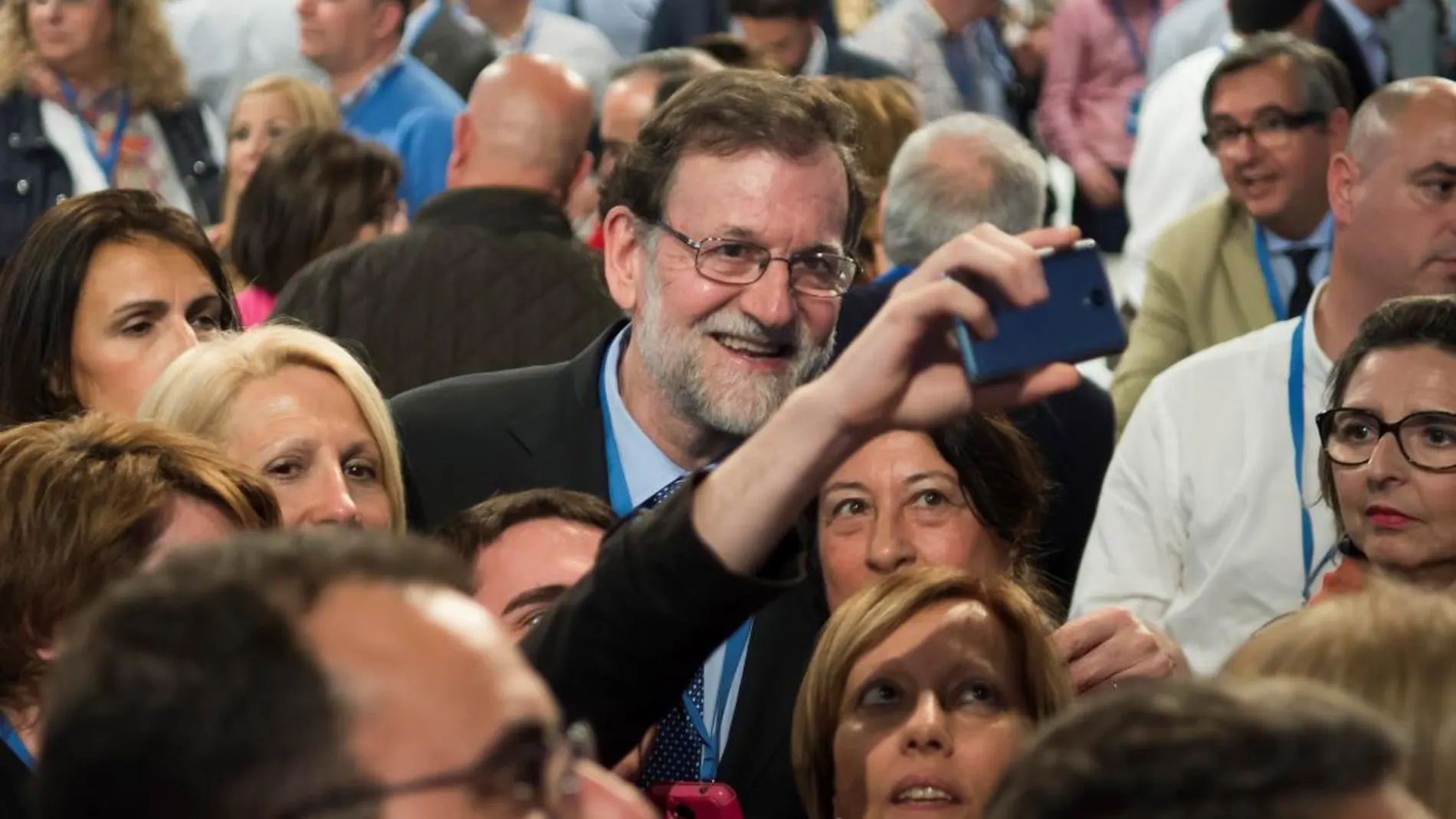 El presidente del Gobierno, Mariano Rajoy, se fotografía con unos asistentes esta tarde a la Convención Nacional del PP