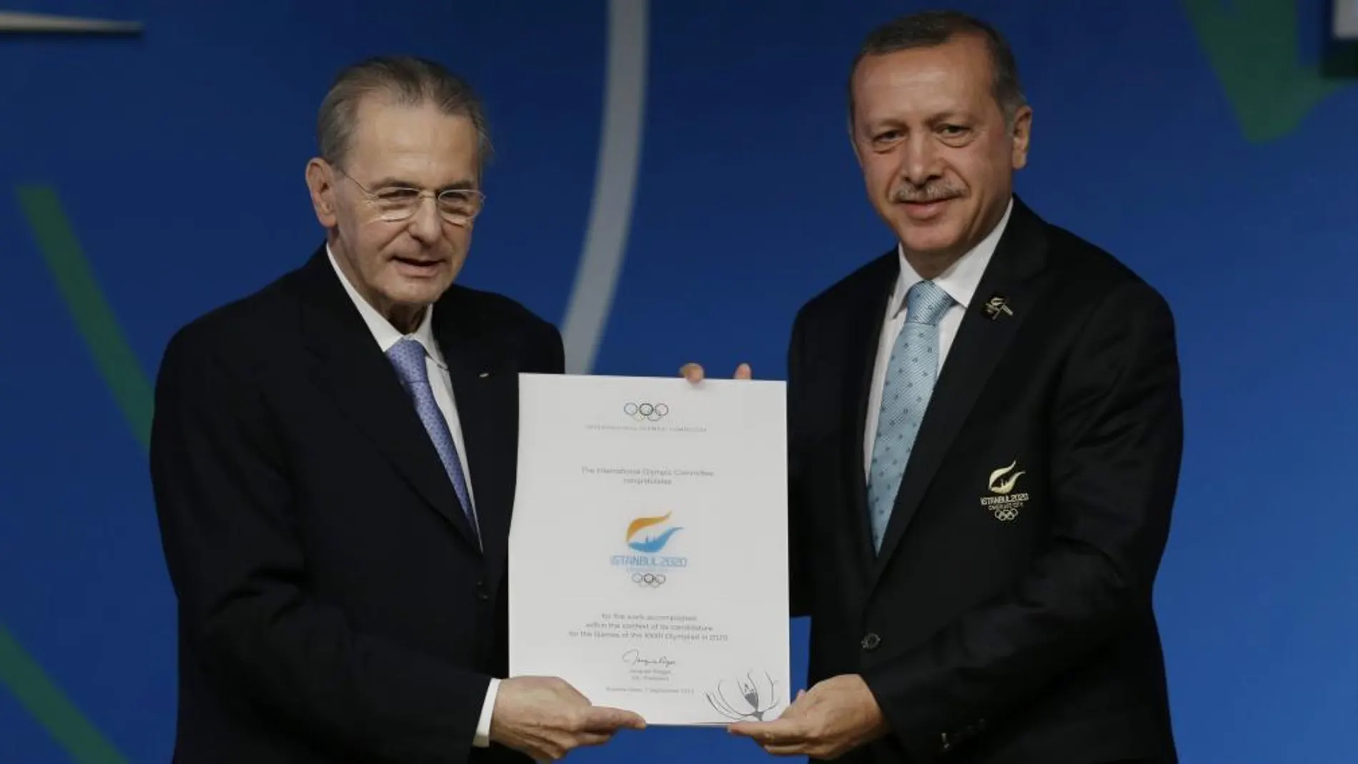 El primer ministro turco recibe del presidente del COI, Jacques Roge, un diploma.
