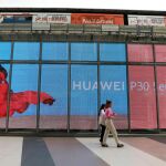 Una mujer pasa junto a un escaparete de una tienda Huawei en Bangkok
