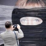 Un hombre hace una foto en Berlín a un cartel de Merkel saboteado con pintura negra