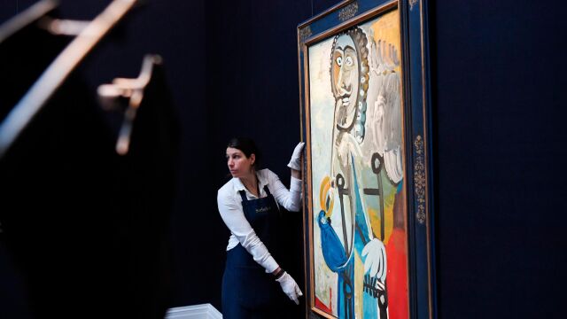 Una empleada de Sotheby's coloca la pintura "Hombre con una pipa", de Pablo Picasso, en la exposición de Arte Impresionista y Moderno en Londres / Foto: Efe