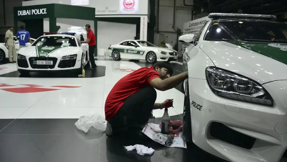 Un operario limpia un coche patrulla en el Dubai Motor Show