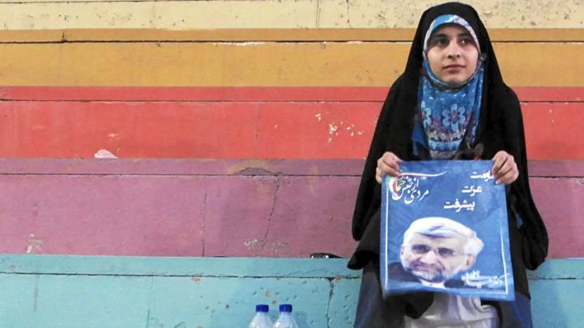 Una mujer iraní sostiene un cartel electoral del candidato ultraconservador Said Jalili tras asistir a un mítin en Teherán