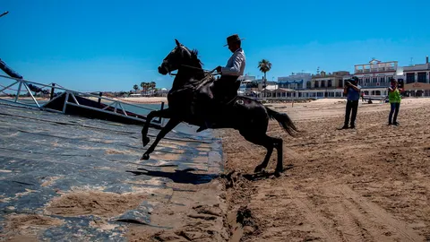 Un caballista se dispone a entrar en la barcaza en Bajo de Guía para cruzar el Guadalquivir / Fotos: Manuel Olmedo y Efe
