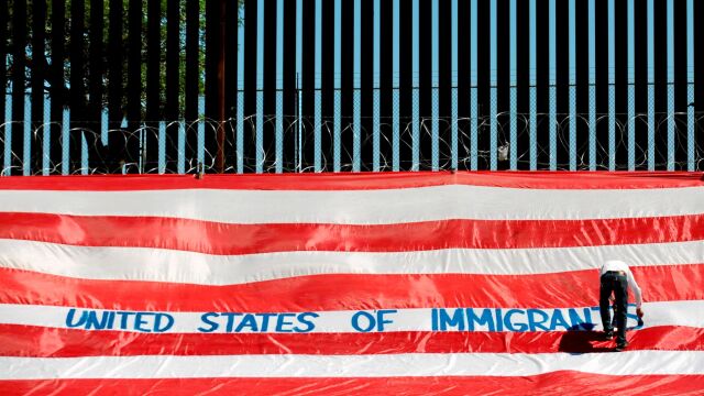 Roberto Márquez coloca un bandera americana en la que ha escrito «EE UU es un país de inmigrantes» en la frontera del Paso (Texas)
