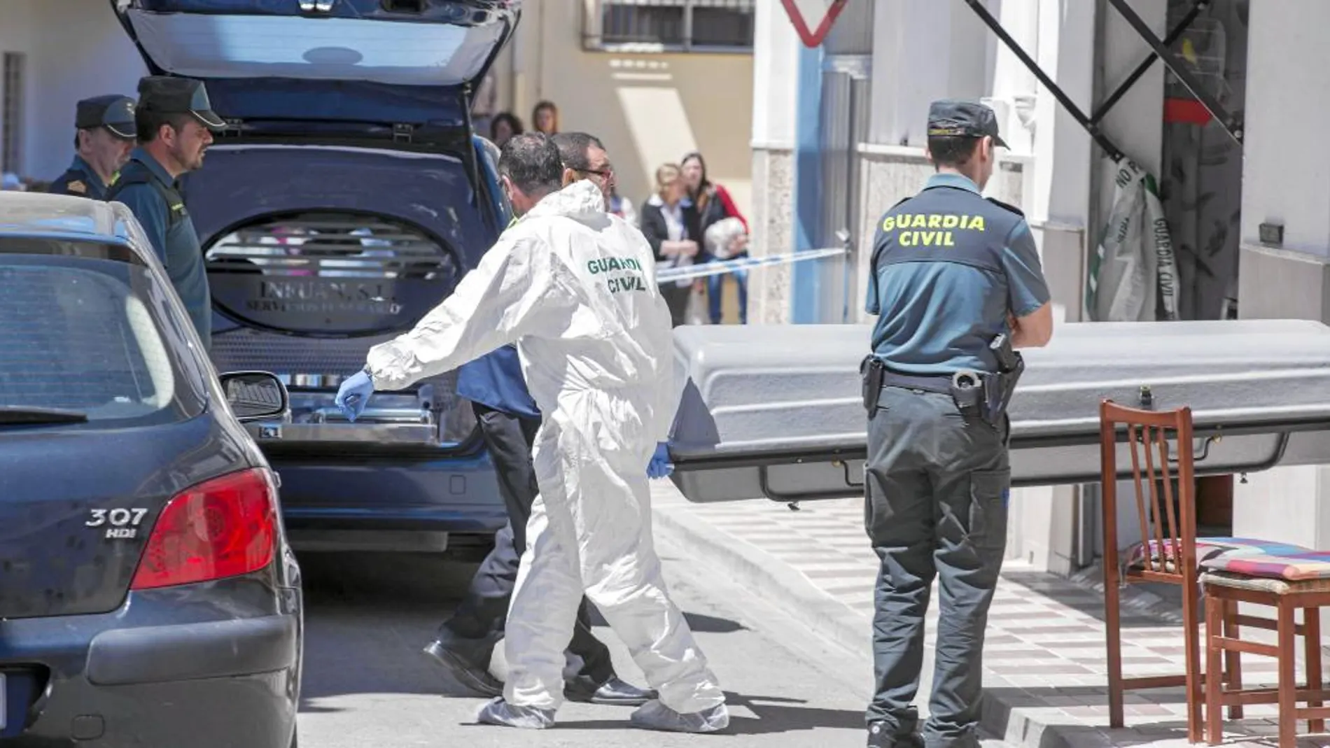 Unos operarios sacan el cuerpo de la mujer de 55 años asesinada ayer en su vivienda en la localidad jiennense de Alcalá la Real