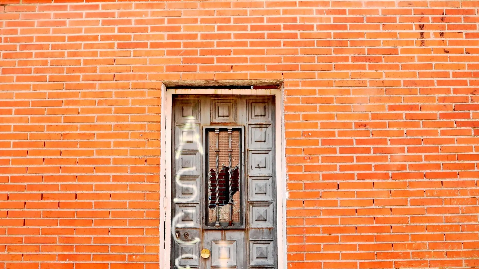 La puerta de la parte de atrás de la casa donde vivía «el Chule» sigue con el cristal roto y con el grafiti que reza «asesinos»