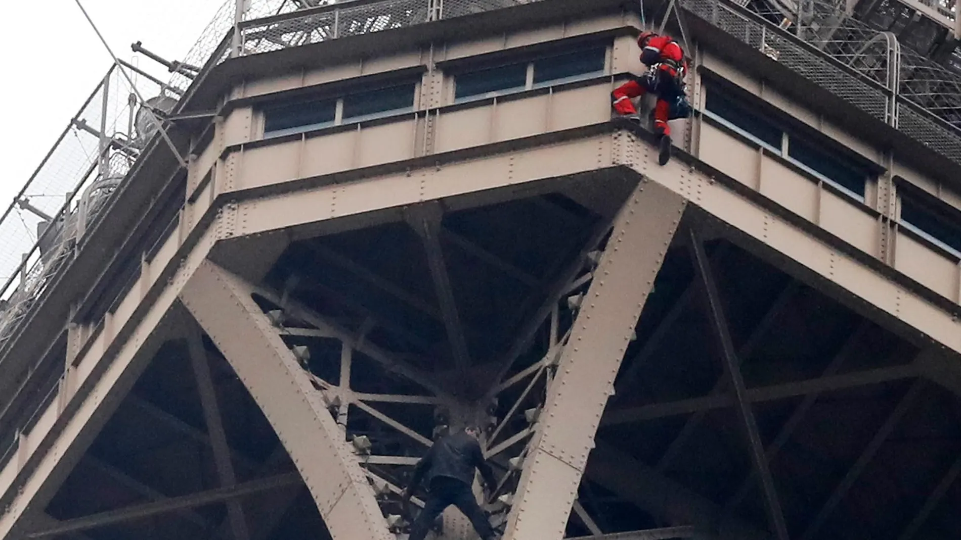 Un escalador ha comenzado a ascender por la estructura de la Torre Eiffel