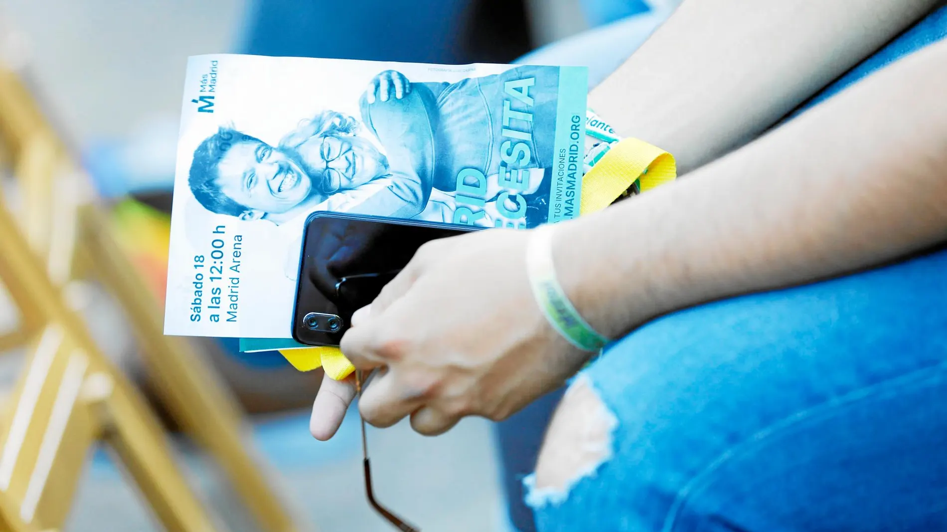 Un asistente al mitin de Madrid Río, ayer, con una de las publicidades electorales de Más Madrid. Foto: JESÚS G. FERIA